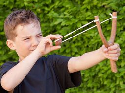 Junge spielt mit einer Steinschleuder